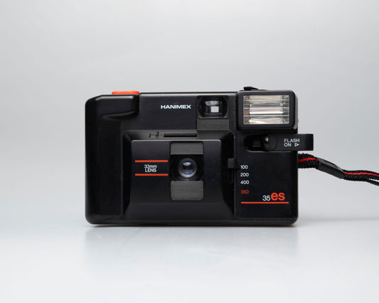 Black Hanimex 35ES camera with flash on a white background available at www.newwavepool.shop