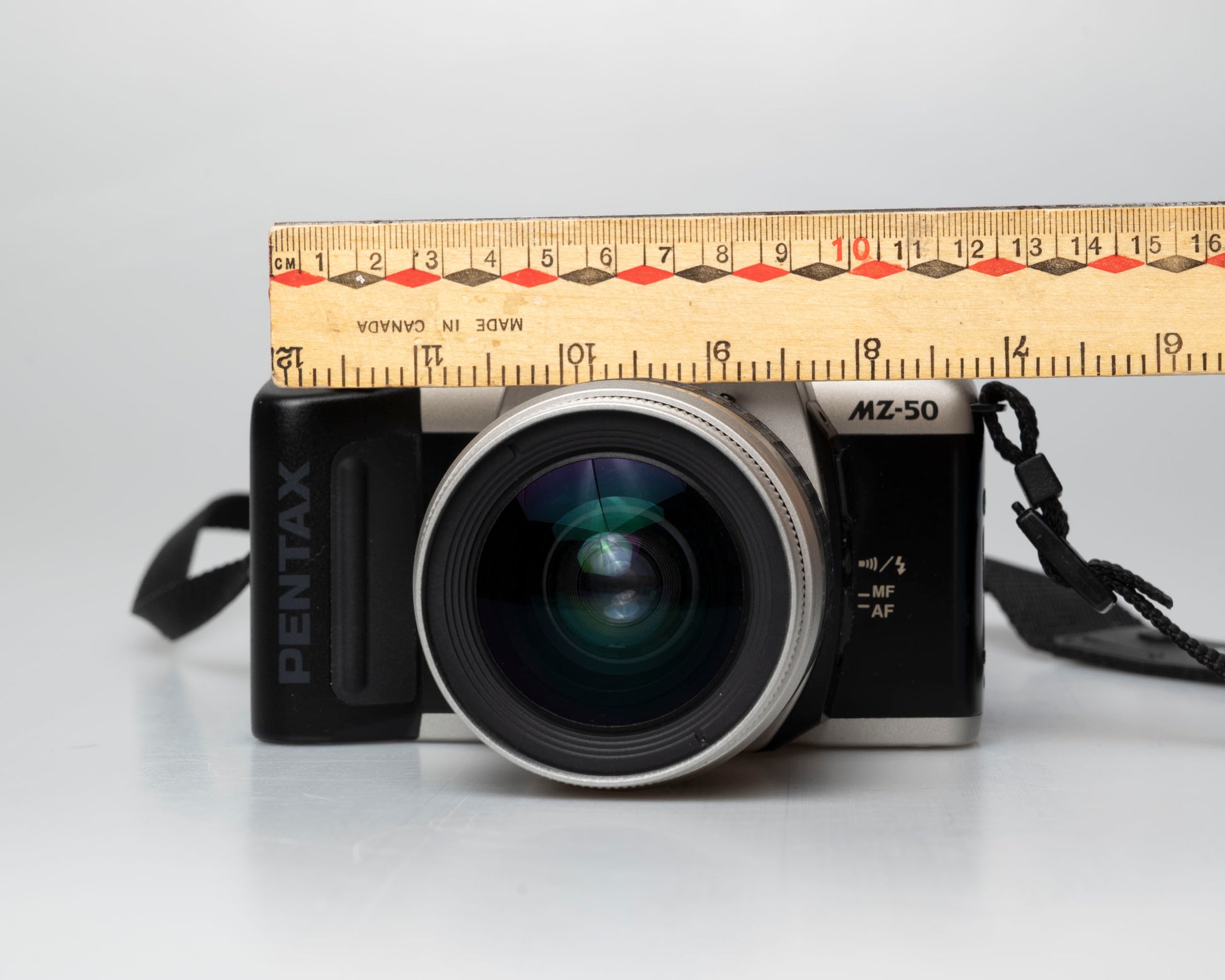 Pentax MZ-50 35mm film camera with kit zoom lens; front view with ruler for scale