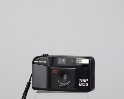 The Olympus Trip MD3 is a simple compact 35mm film camera featuring a fixed 34mm lens